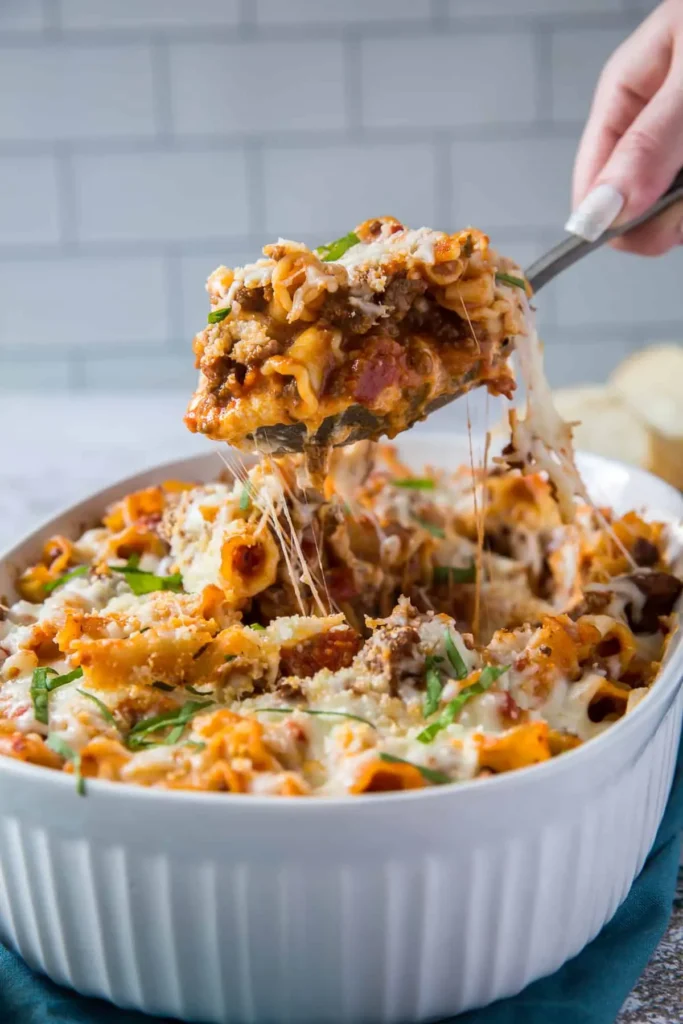 Lazy lasagna in a casserole dish with a huge spoonful being held in someone's hand.