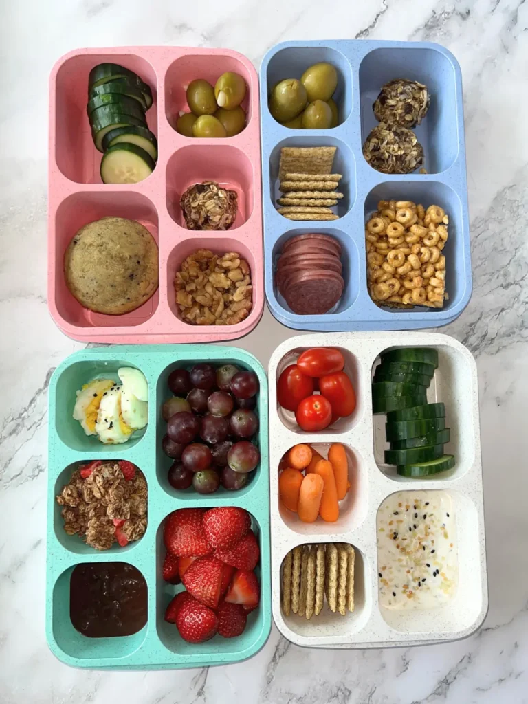 4 snack boxes of various colors filled with different snacks on a counter.