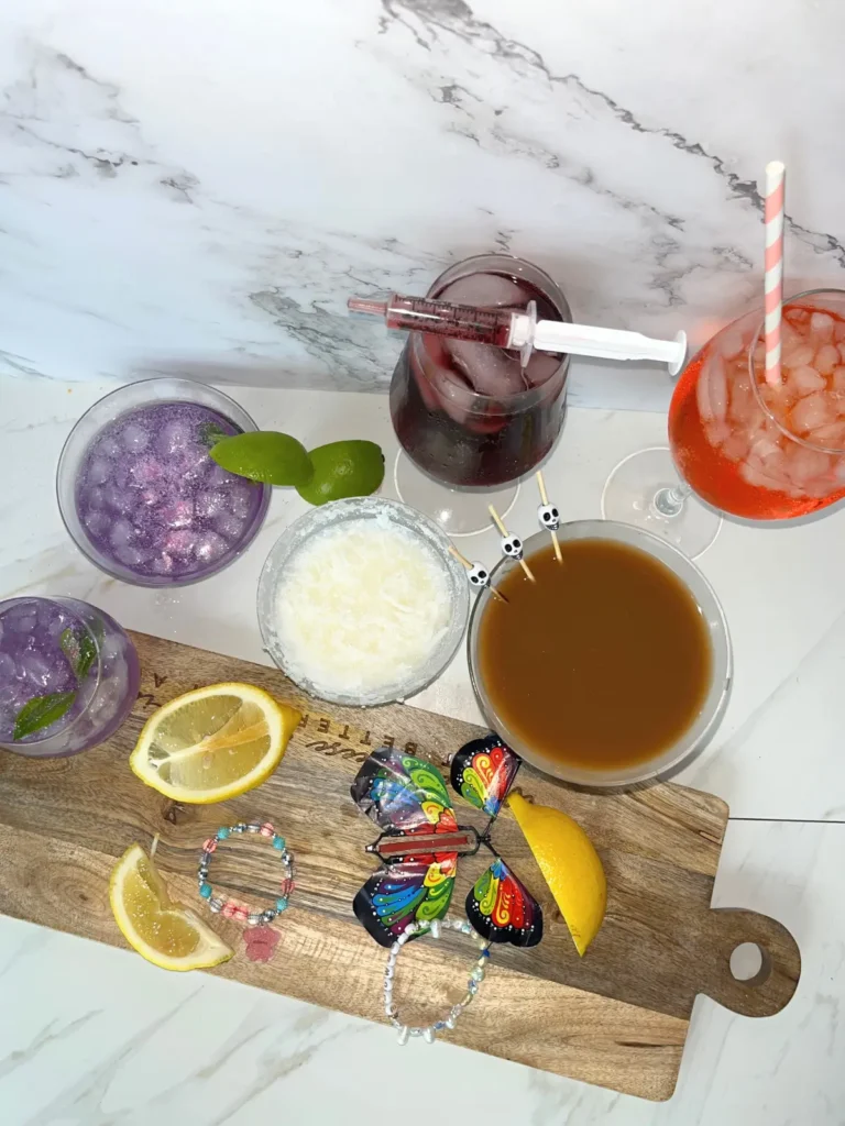 6 Taylor Swift inspired cocktails next to a napkin holder with friendship bracelets on a counter.