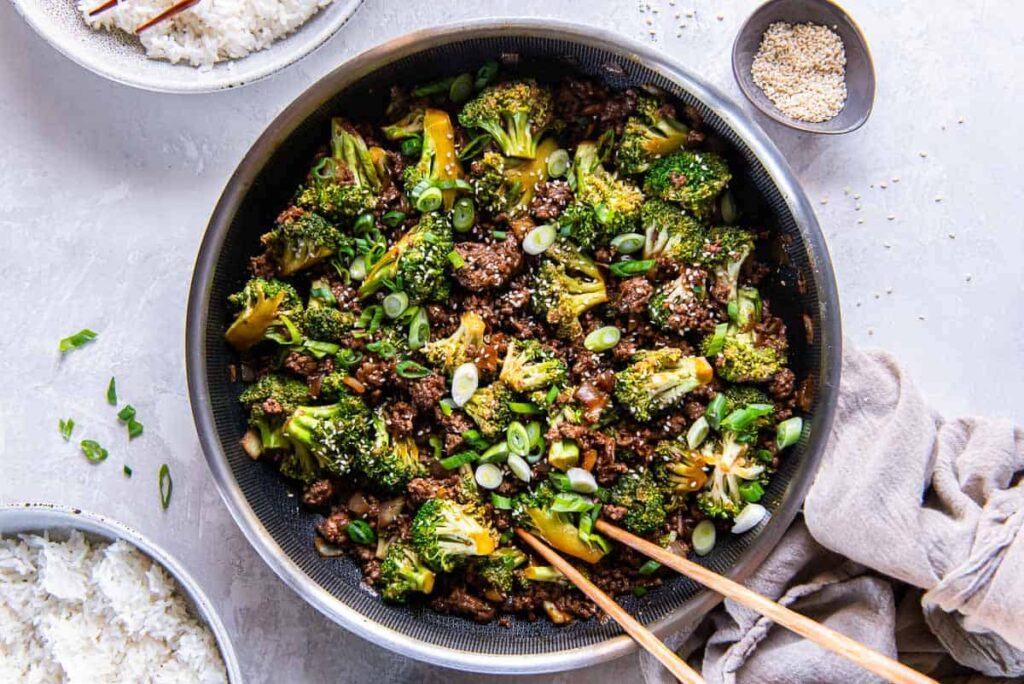 Asian inspired ground beef and broccoli topped with sesame seeds in a pan on a table.