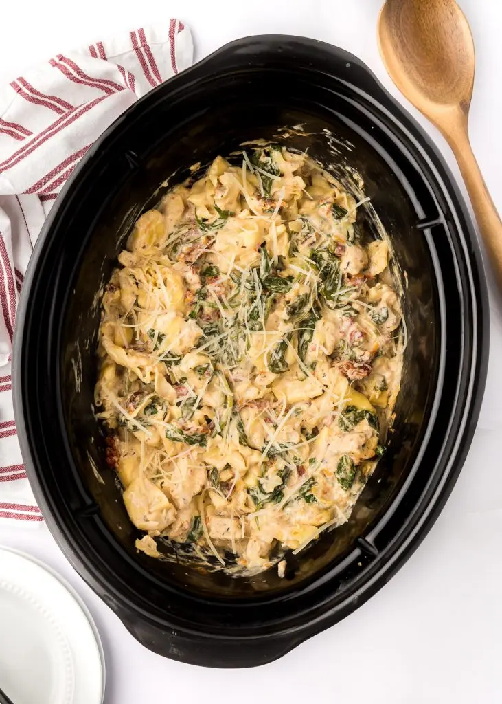 Tuscan chicken tortellini in a crockpot after baking on a table.