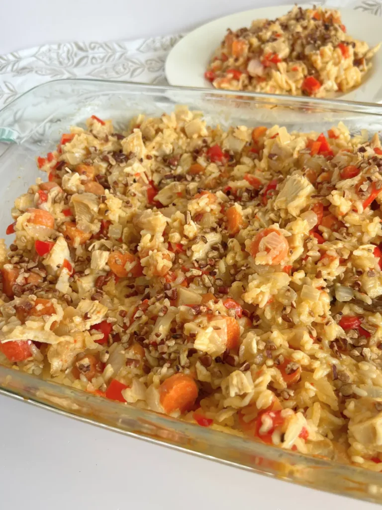 Coconut chicken casserole in a 9 x 13 baking dish on a counter with a plate of it in the background.