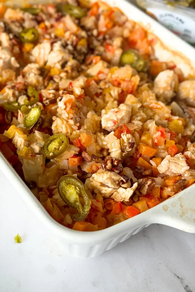 The fully assembled creamy coconut chicken casserole in a white casserole dish on a counter.