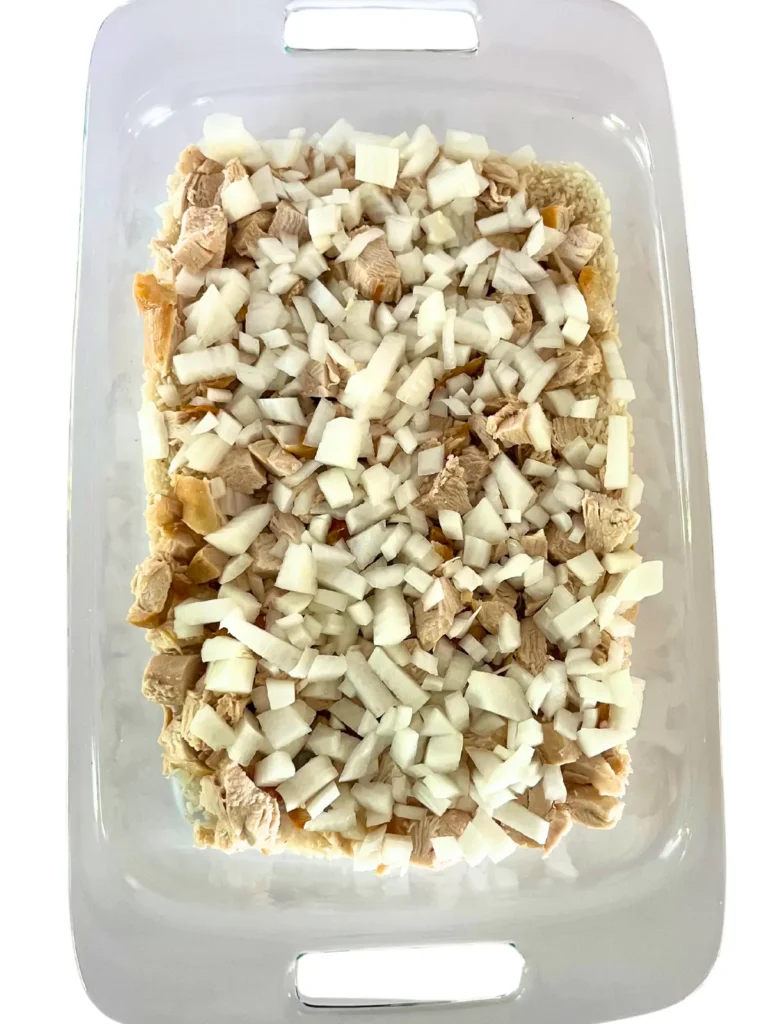 Diced chicken, onion, and rice in a 9x13 baking dish.