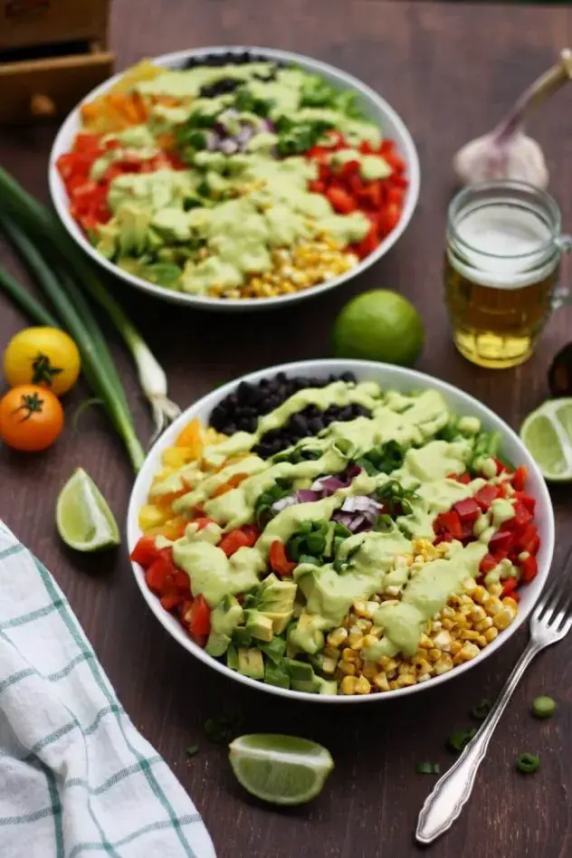 Two vegan chopped salads packed with fresh veggies and black beans on a table.