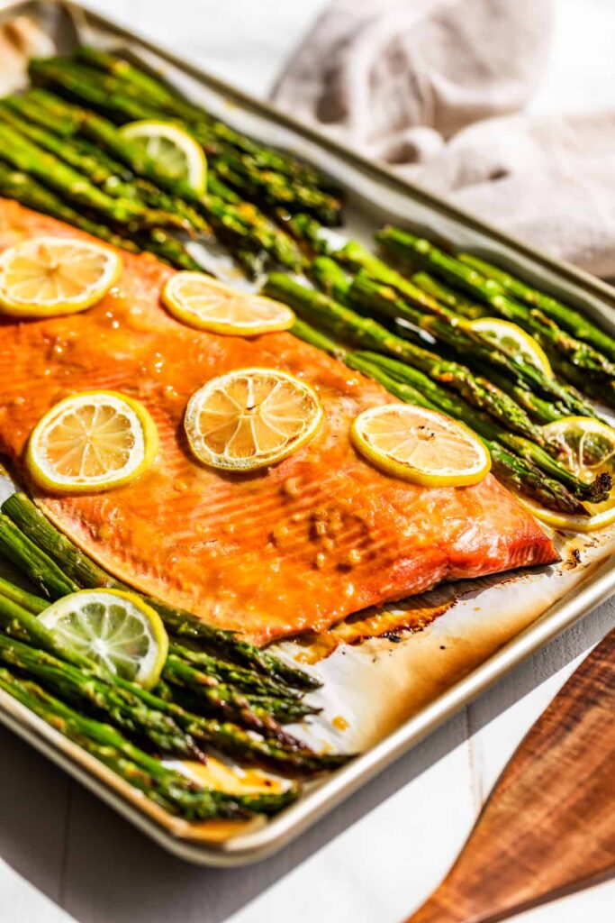 Roasted salmon and asparagus on a sheet pan on a table.