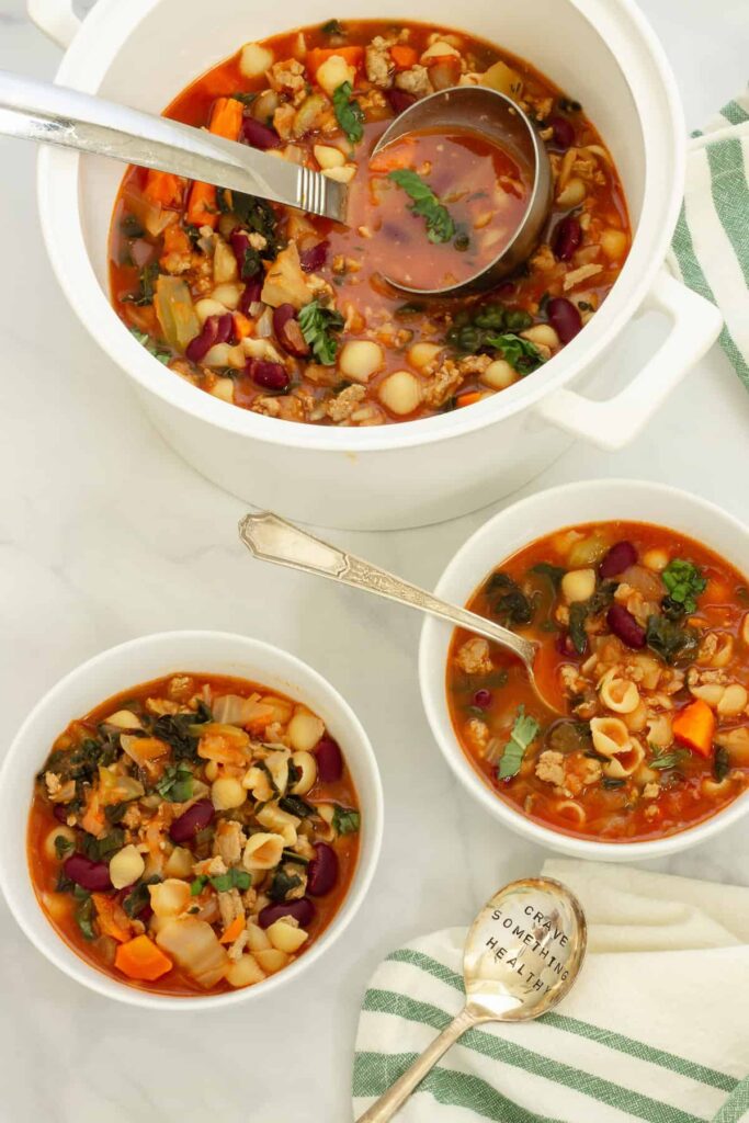 Two bowls of ground turkey soup on a table next to a large pot of it.