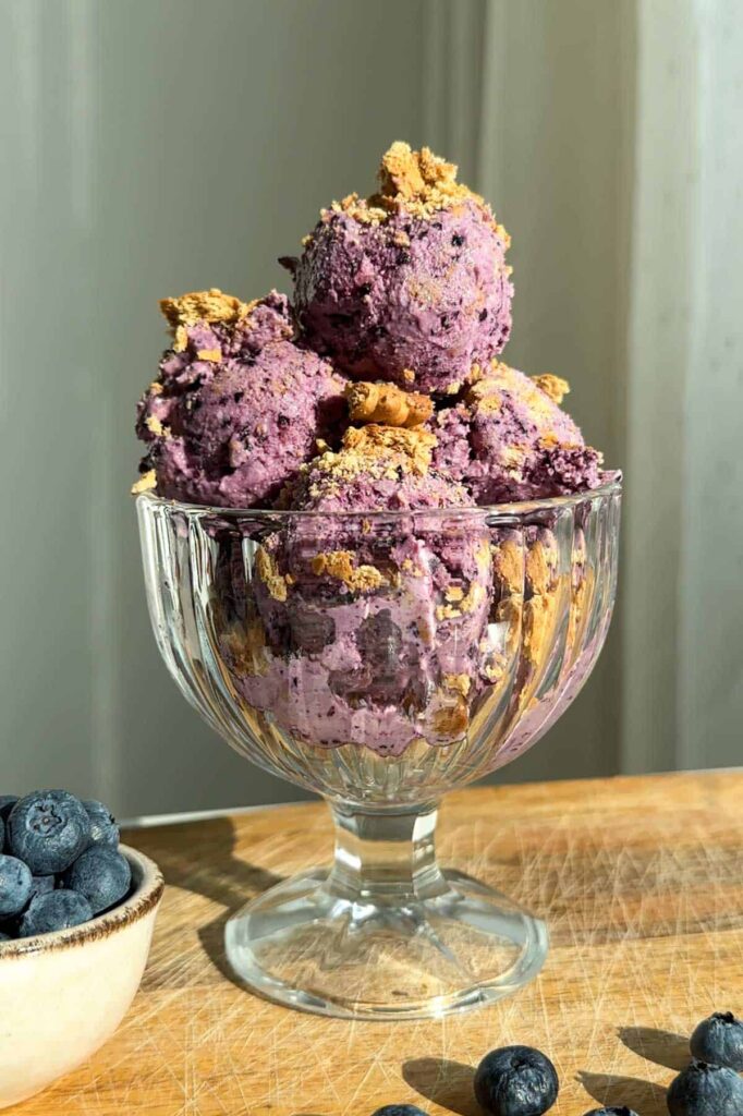 Scoops of cottage cheese blueberry pie ice cream in a large bowl on a table.