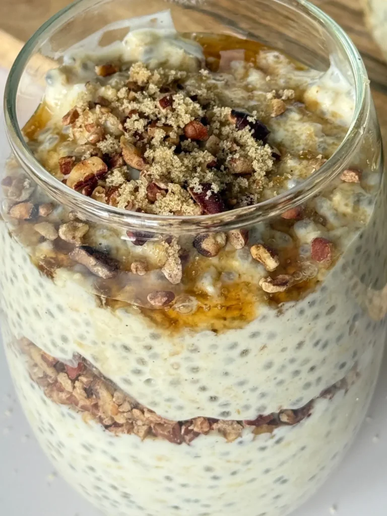 A close-up of a glass jar of maple pecan brown sugar overnight oats on a counter.