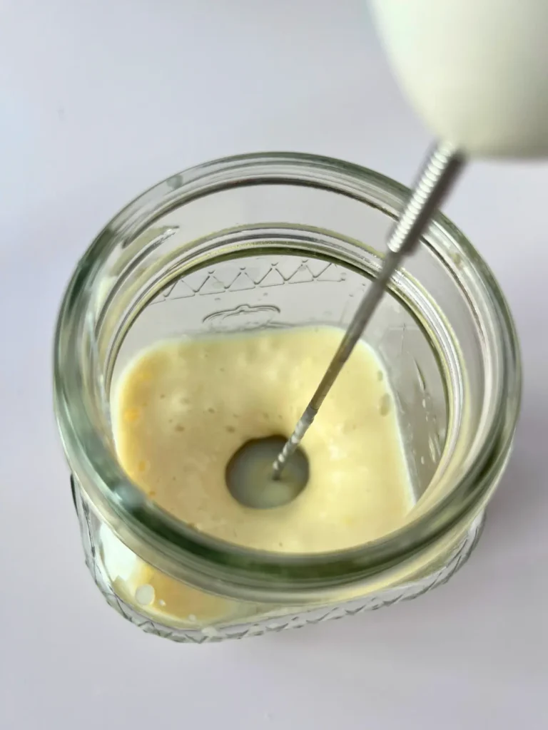 A hand frother mixing the cold foam ingredients in a mason jar.