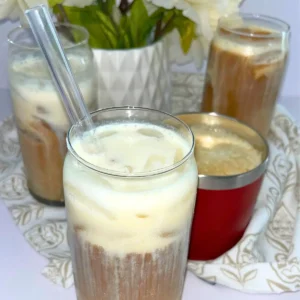 4 protein coffees on a counter next to a pot of flowers.