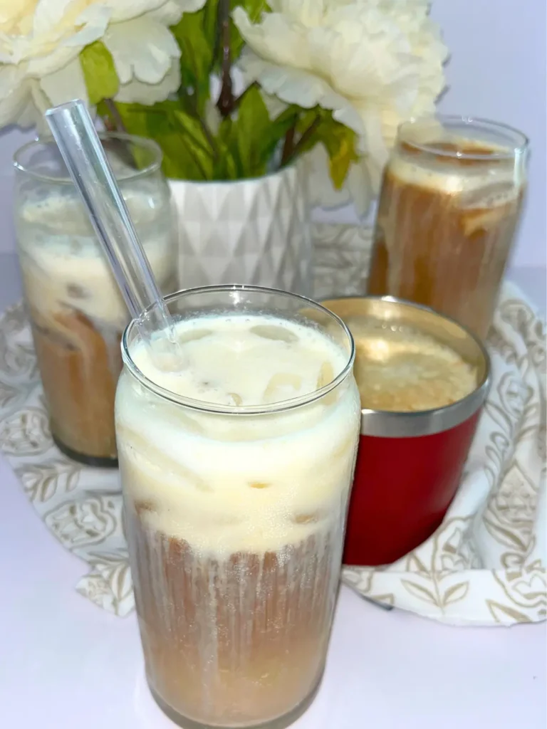 4 protein coffees on a counter next to a pot of flowers.