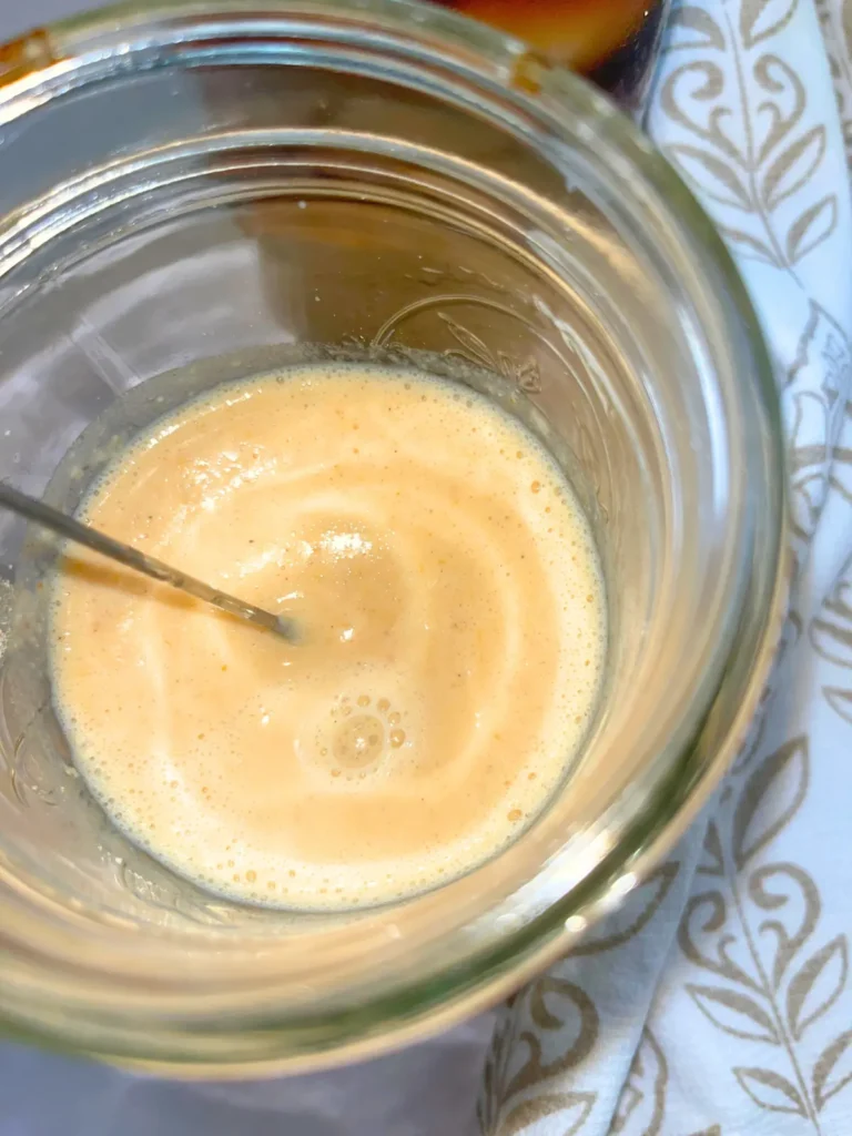 A hand frother mixing the pumpkin spice cold foam.