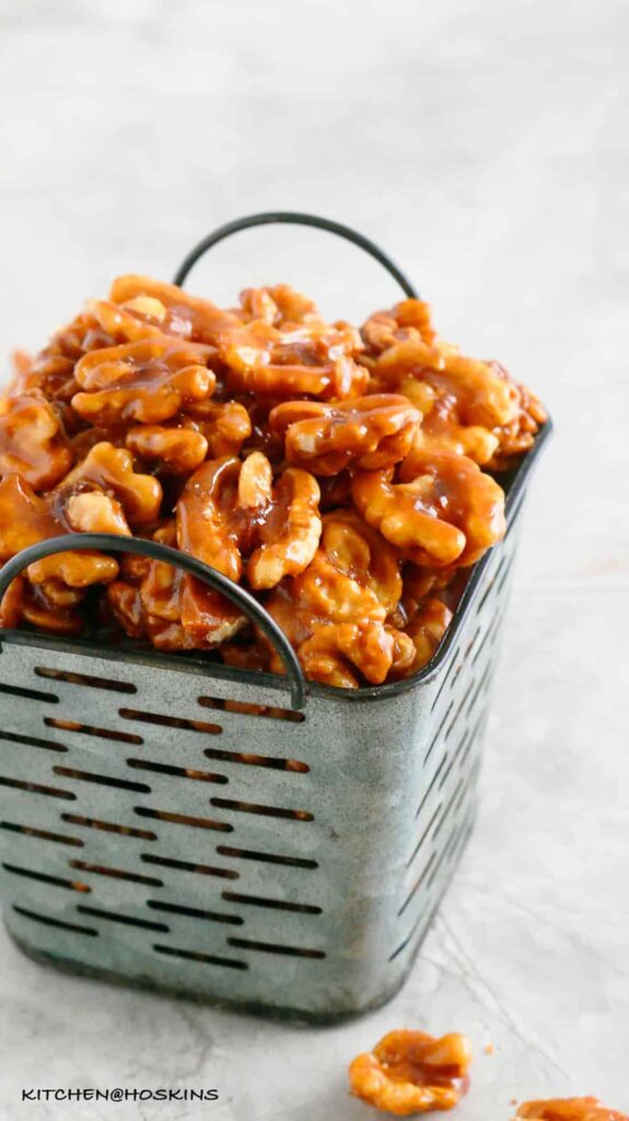 Caramelized walnuts in a blue decorative bowl on a counter.