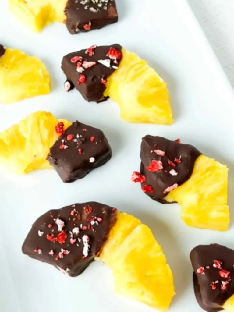 Pineapple slices dipped in chocolate on a white platter.