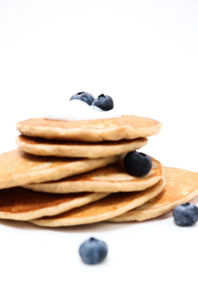 Easy protein pancakes stacked on top of one another with yogurt and blueberries on top.