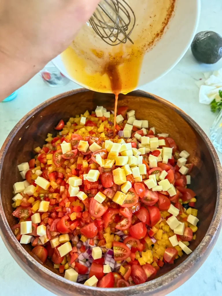 Pouring the dressing onto the dense bean salad in a large bowl.