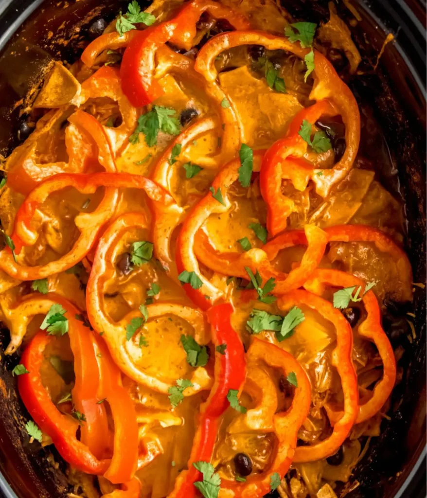 A birds-eye view of chicken enchiladas in a slow cooker.