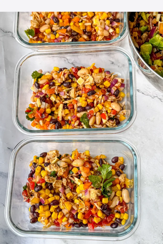 Meal prep containers with the bean salad in each one on a counter.