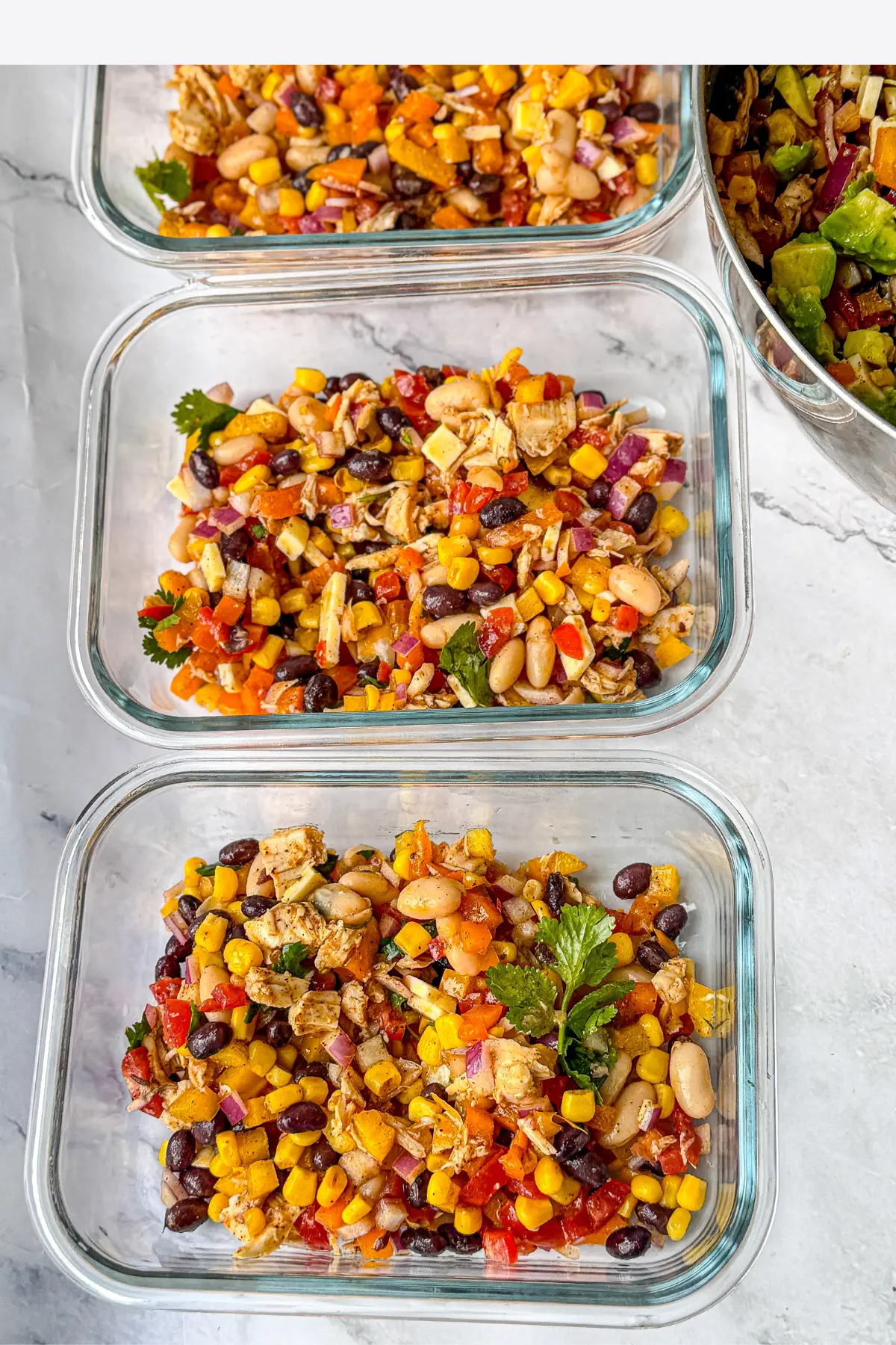 Meal prep containers with the bean salad in each one on a counter.
