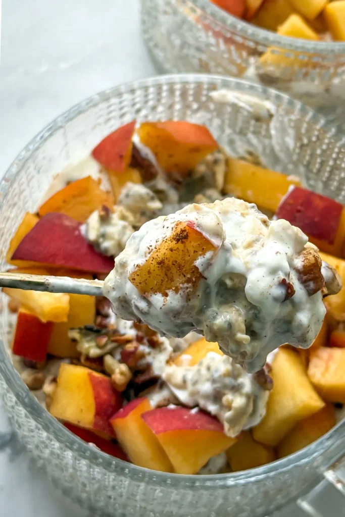 A close-up of a big spoonful of peach overnight nights topped with vanilla yogurt and cinnamon.