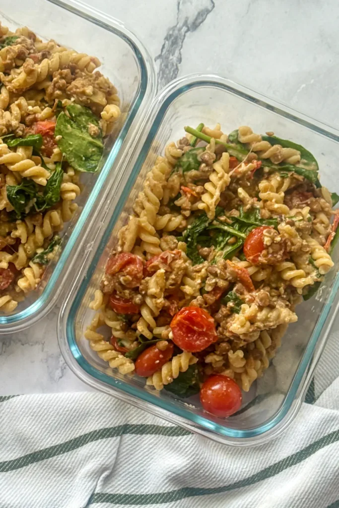 Two meal prep glass containers with feta pasta in them.