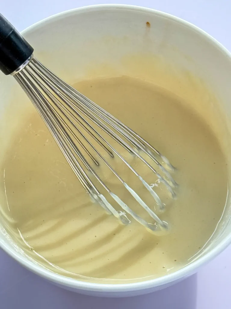 Whisking the cinnamon roll pudding mixture until smooth.