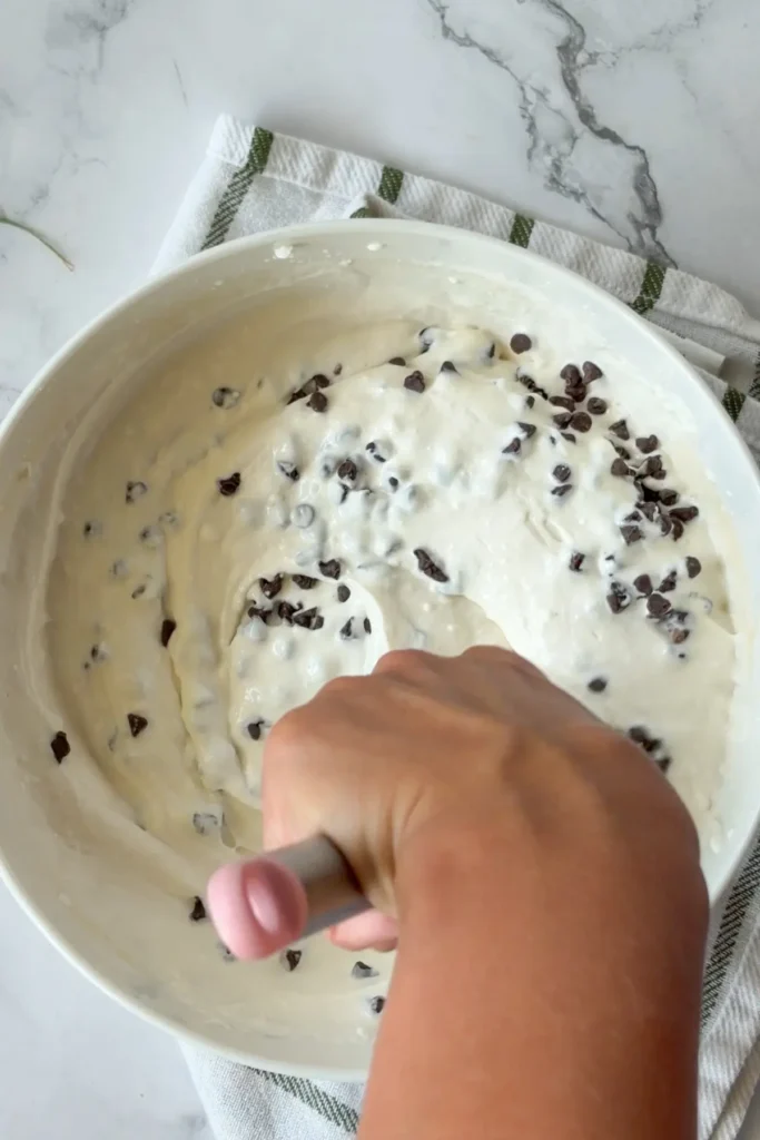 Stirring mini chocolate chips into the cottage cheese dip.