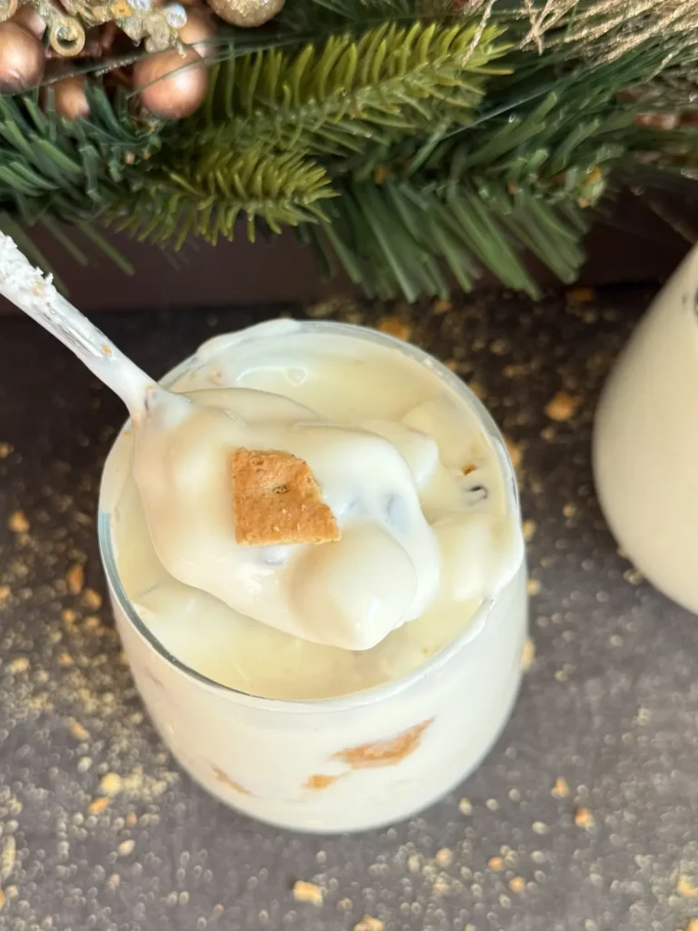 A close-up of a spoonful of s'mores Greek yogurt pudding with a glass of it underneath the spoon.