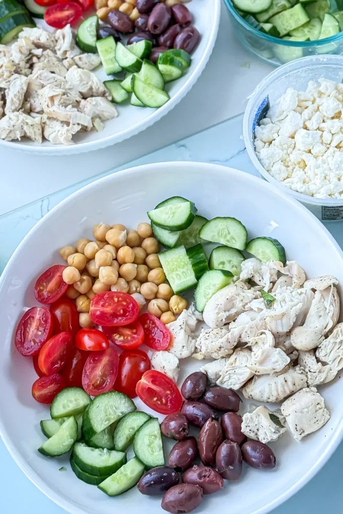 Assembling the Greek chicken protein bowl before sprinkling on cheese and yogurt.