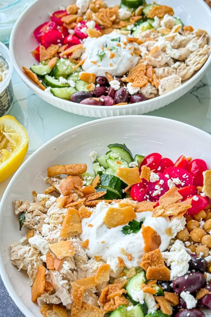 Two fully assembled Greek chicken protein bowls on a table.
