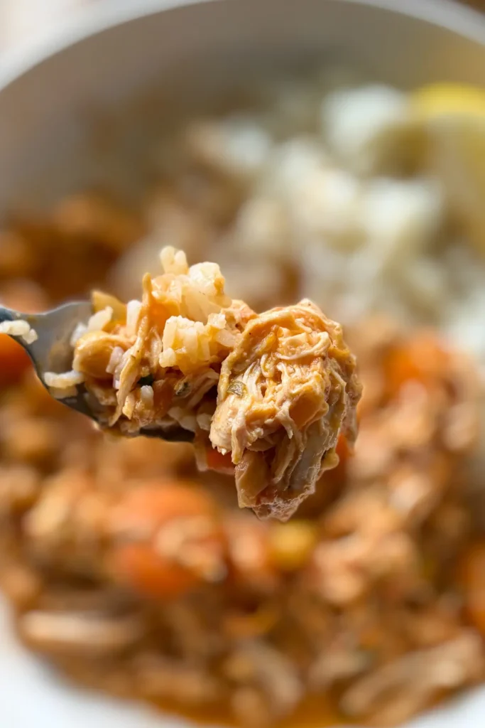 A close-up of a forkful of coconut tomato chicken with carrots.