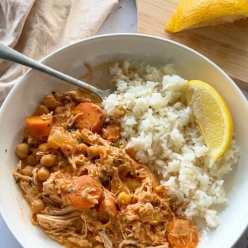 A birds-eye view of a white plate with the chicken mixture and rice on it on a table.