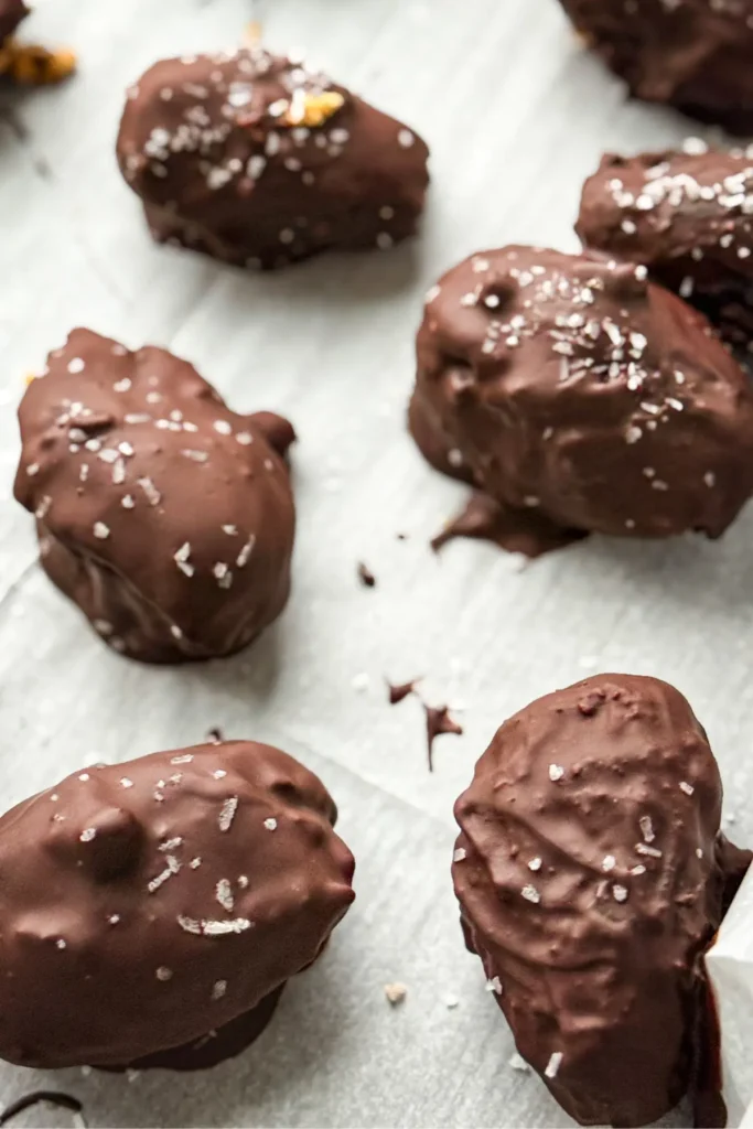 A birds-eye view of dark chocolate covered protein dates with sea salt on a sheet of parchment paper after freezing.