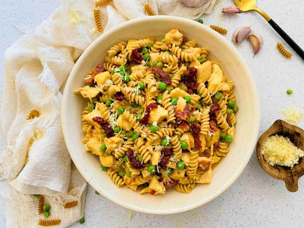 A bowl of chicken Alfredo on a table.