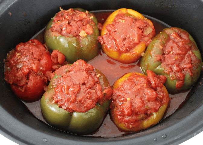 A birds-eye view of 6 stuffed peppers in a slow cooker.