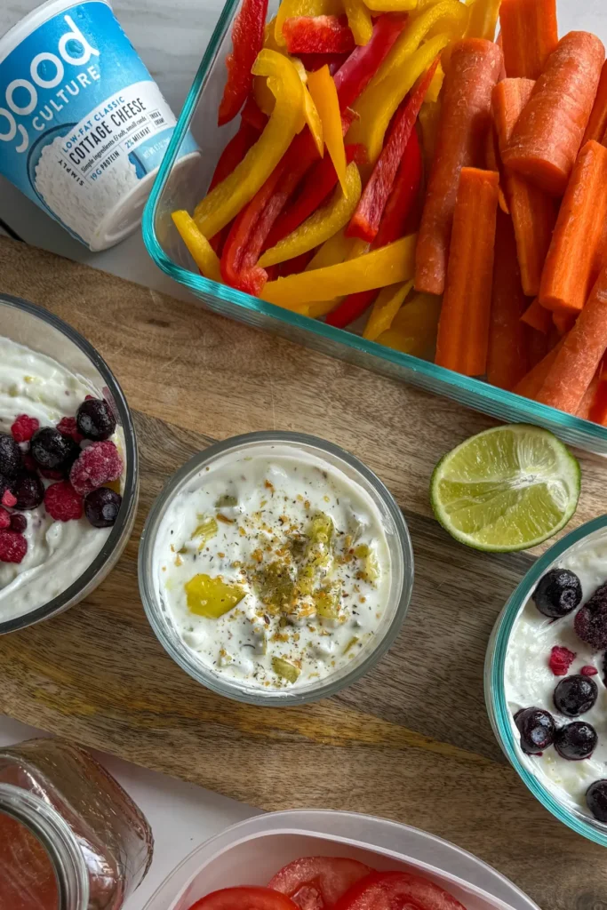 Two Greek yogurt parfaits in glass Pyrex dishes and a glass container with freshly chopped veggies.