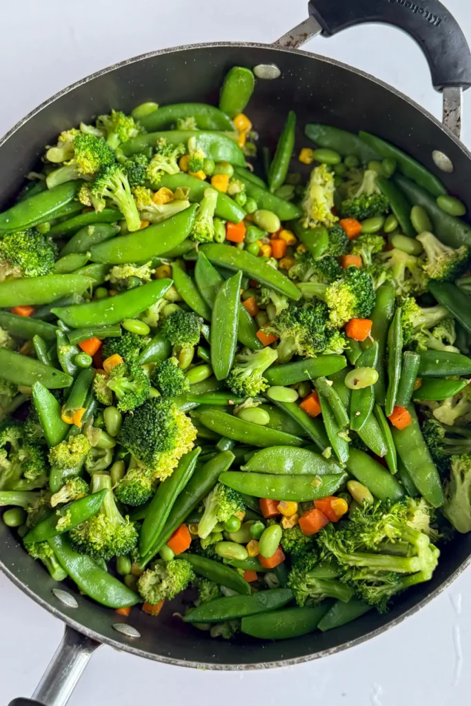 A variety of vegetables cooking in a pan.