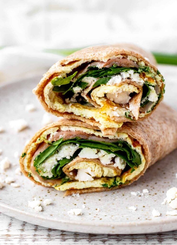 A smoked salmon wrap cut in half and stack on top of each other on a plate.