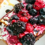 A birds-eye view of toast topped with whipped cottage cheese, fresh berries and balsamic glaze.