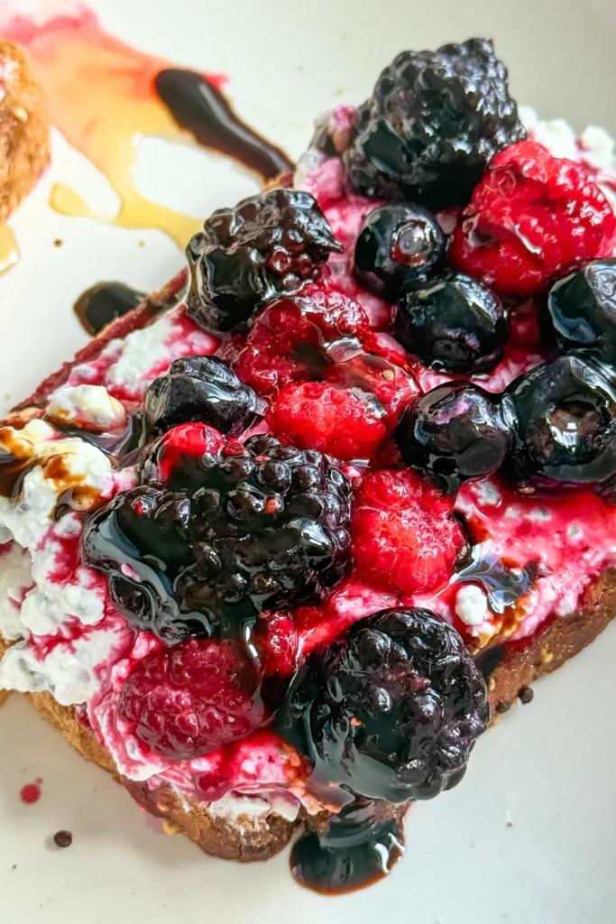 A birds-eye view of toast topped with whipped cottage cheese, fresh berries and balsamic glaze.