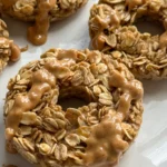 A close-up of baked donuts on a white platter drizzled with peanut butter.