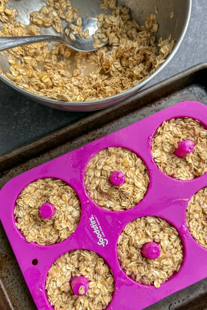 Filled donut molds with batter next to a bowl of baked oatmeal batter.
