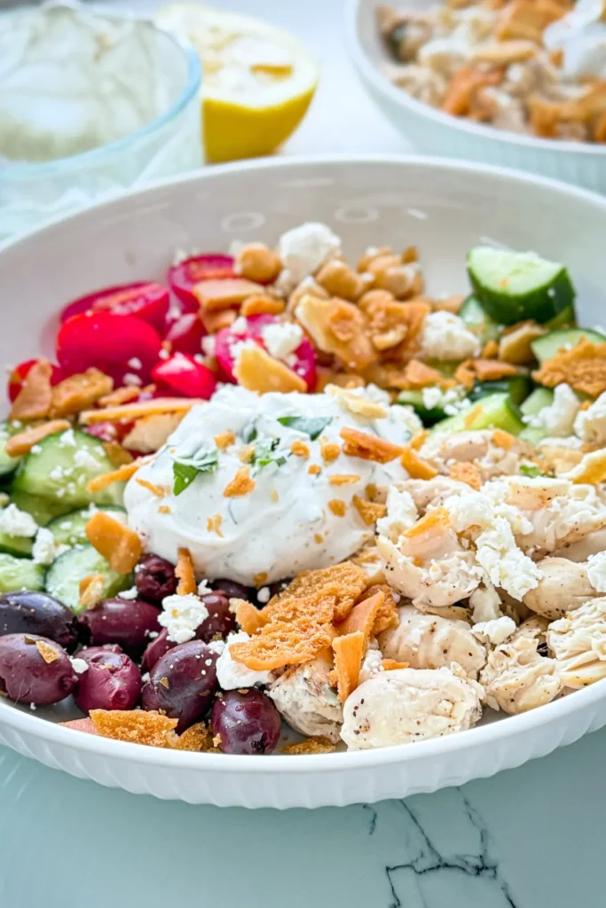 A close-up of a Greek chicken protein bowl on a table next to a lime wedge.