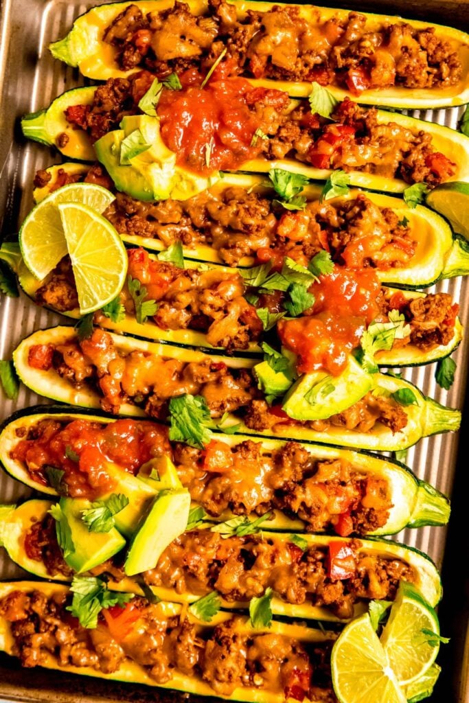 A birds-eye view of halved zucchini with taco meat in it on a baking sheet after cooking. 