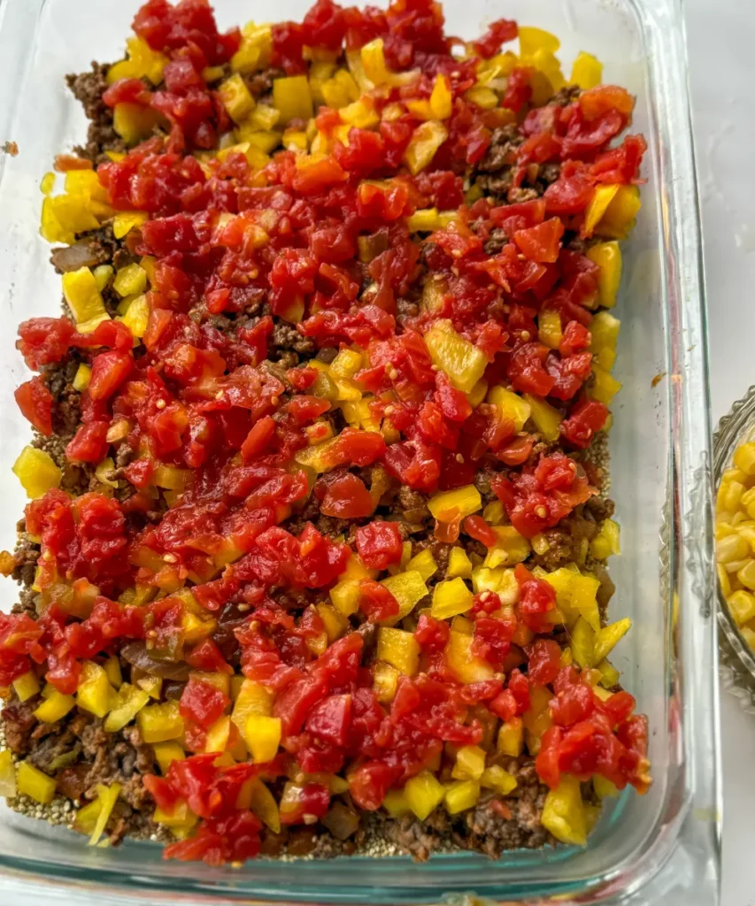 Ground beef, bell peppers and tomatoes layered in a casserole dish.