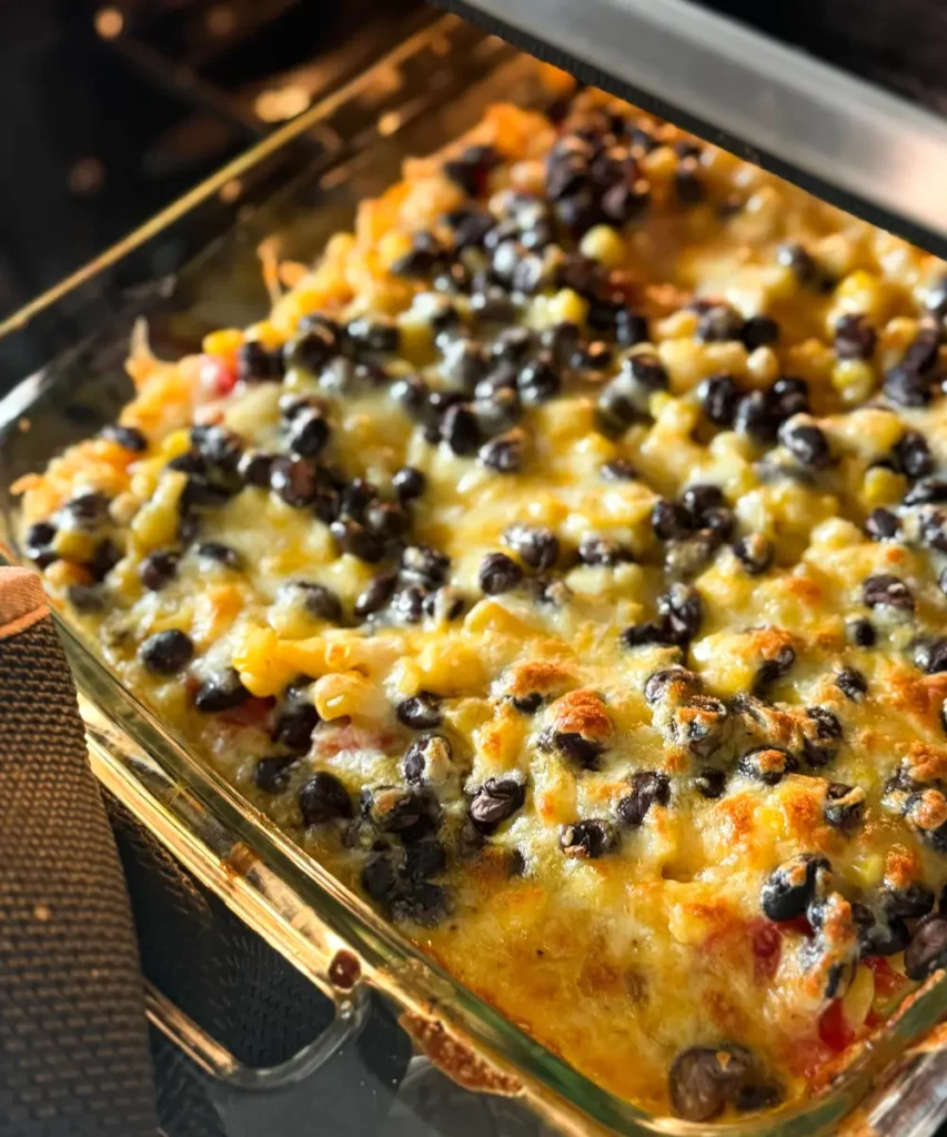 A baked Mexican quinoa casserole with melted cheese being pulled out of the oven.