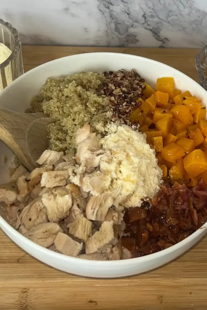 A butternut squash bowl with chicken, parmesan, bacon and nuts on a table.