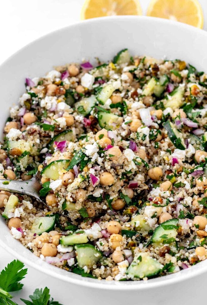 Chickpeas, cucumber, quinoa and herb salad in a large white bowl.
