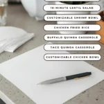 A piece of pen and a paper on a counter in the kitchen with text on the screen listing the 7 easy dinner ideas for this meal plan.